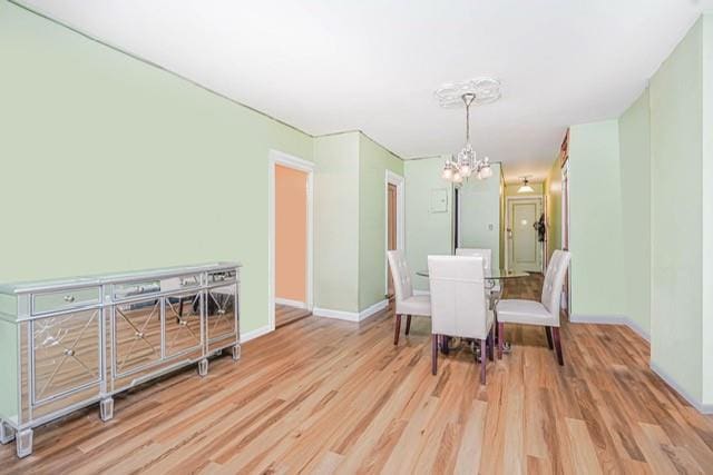 dining room with a chandelier, wood finished floors, and baseboards