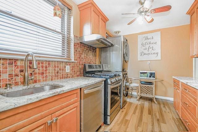 kitchen with appliances with stainless steel finishes, a sink, tasteful backsplash, and light wood finished floors
