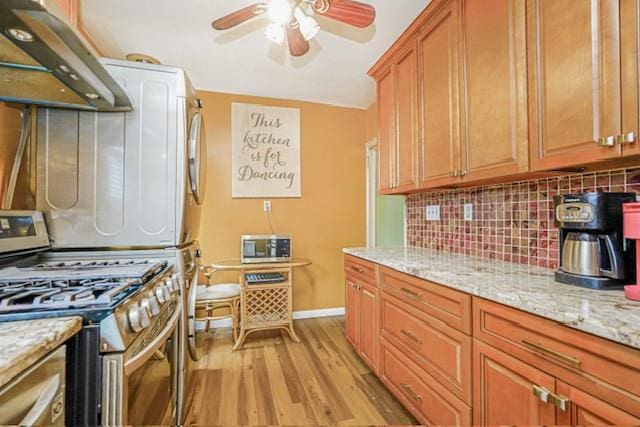 kitchen with stainless steel gas range, under cabinet range hood, a ceiling fan, tasteful backsplash, and light wood-type flooring