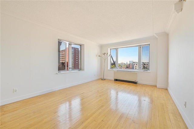empty room with ornamental molding, radiator, a textured ceiling, and hardwood / wood-style floors