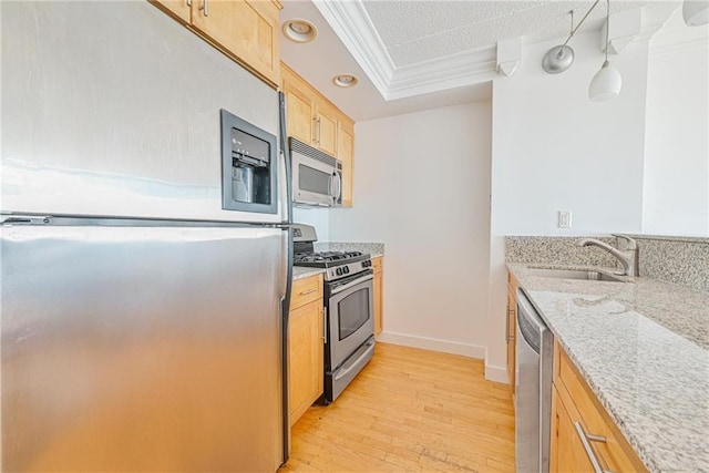 kitchen featuring crown molding, light stone countertops, a sink, light wood finished floors, and stainless steel appliances