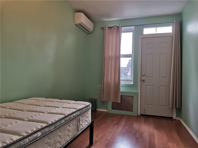 entryway featuring radiator, a wall mounted air conditioner, wood finished floors, and baseboards