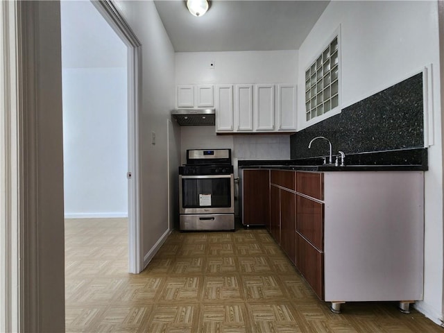 kitchen featuring stainless steel range with gas stovetop, extractor fan, a sink, dark countertops, and white cabinets