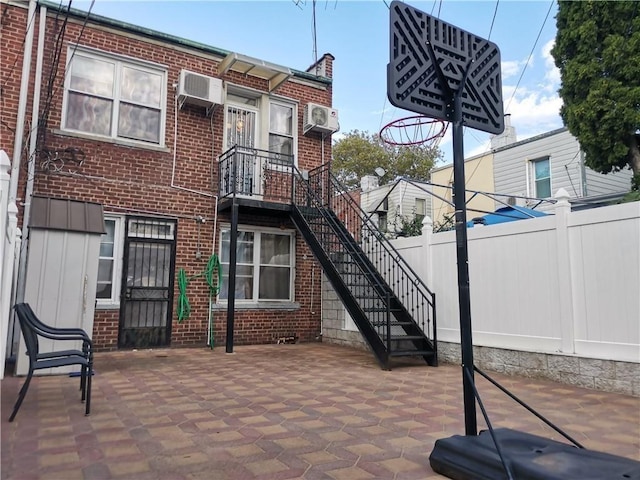 view of patio / terrace with fence and an AC wall unit