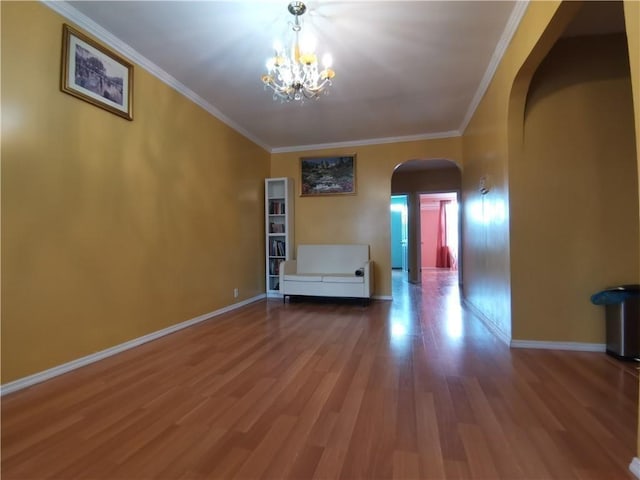 unfurnished living room featuring arched walkways, a chandelier, wood finished floors, baseboards, and ornamental molding
