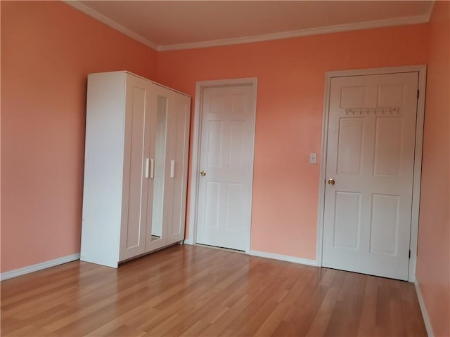 unfurnished bedroom with ornamental molding, light wood-style floors, and baseboards