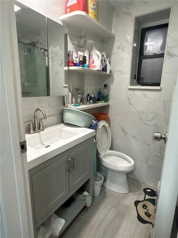 bathroom featuring a stall shower, tile walls, toilet, and vanity