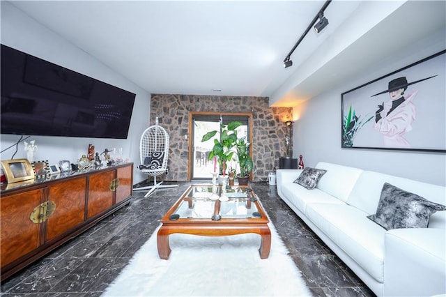 living room featuring marble finish floor, an accent wall, and rail lighting