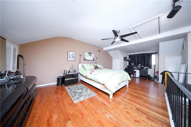 bedroom featuring attic access, vaulted ceiling, wood finished floors, and a ceiling fan