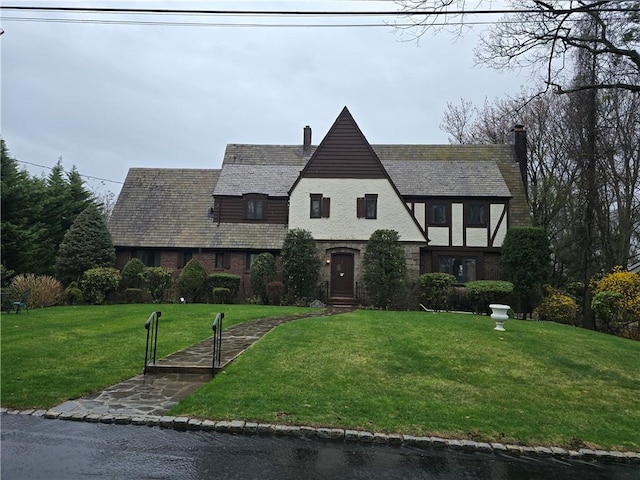 tudor house with a chimney, a front yard, and a high end roof