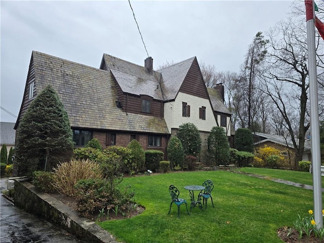 view of property exterior featuring a yard, a chimney, a high end roof, and brick siding