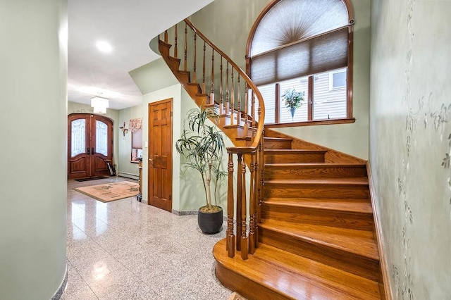 stairway featuring granite finish floor, a baseboard heating unit, and baseboards