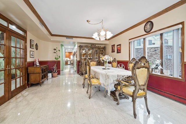 dining space with wainscoting, ornamental molding, french doors, and a chandelier