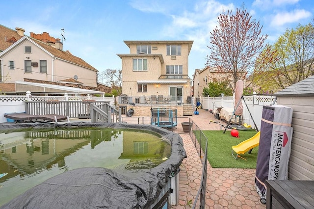 rear view of property featuring a fenced backyard and a playground