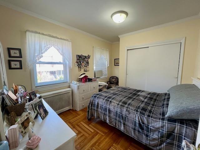 bedroom with radiator, crown molding, and a closet