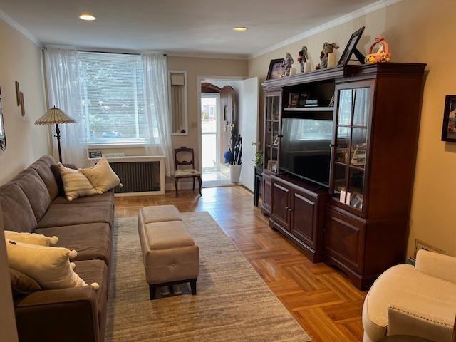 living room with radiator, crown molding, and recessed lighting