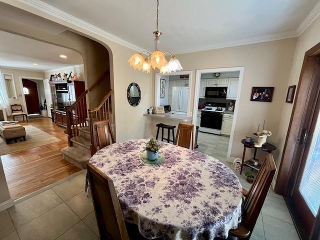 dining space featuring stairs, ornamental molding, a chandelier, arched walkways, and light tile patterned floors