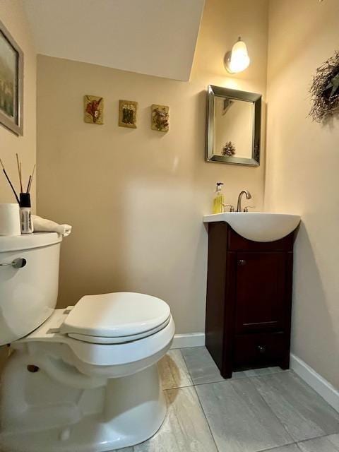 bathroom with toilet, vanity, and baseboards