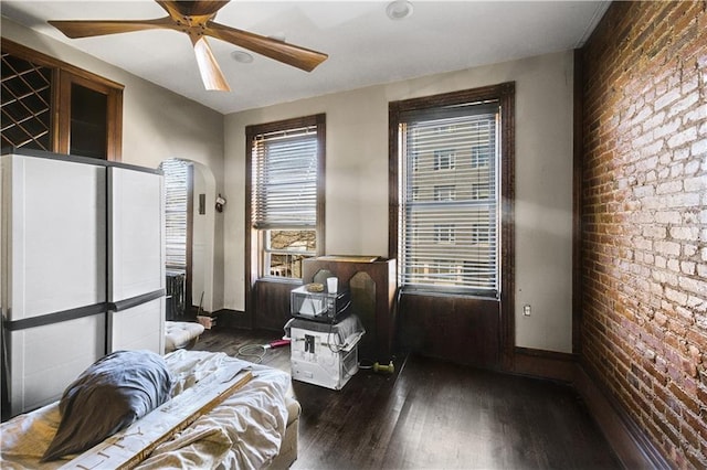 sitting room with brick wall, ceiling fan, baseboards, and wood finished floors