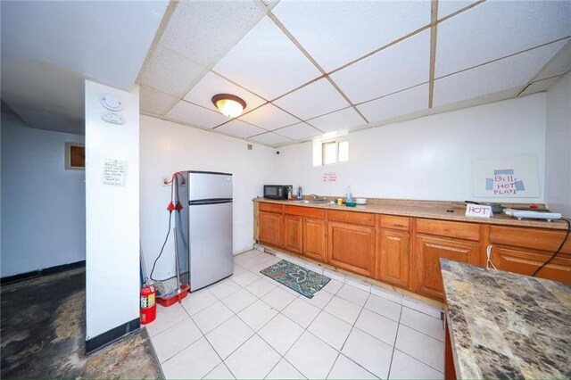 2939 Brighton 3rd St, Brooklyn, NY 11235 - kitchen featuring black microwave, brown cabinets, a sink, freestanding refrigerator, and a drop ceiling