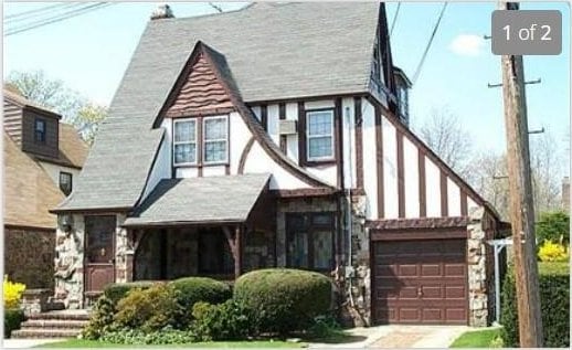tudor house featuring stone siding and driveway