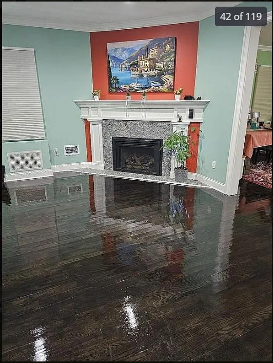 detailed view of a fireplace, wood finished floors, crown molding, and baseboards