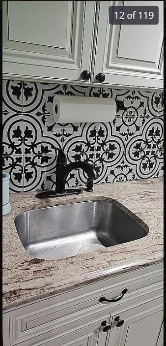 detailed view of pot filler, light stone counters, and white cabinets