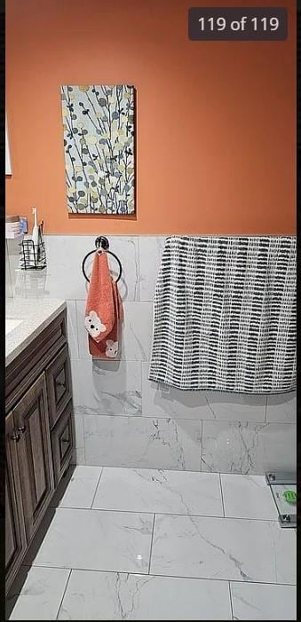 bathroom with marble look tile flooring and vanity