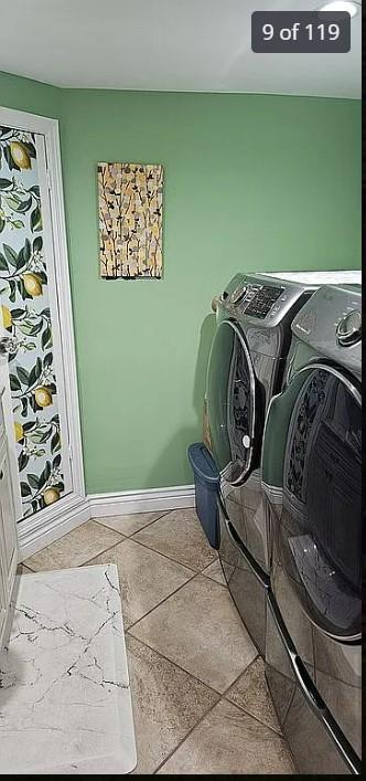 clothes washing area featuring washer and dryer, baseboards, and light tile patterned floors