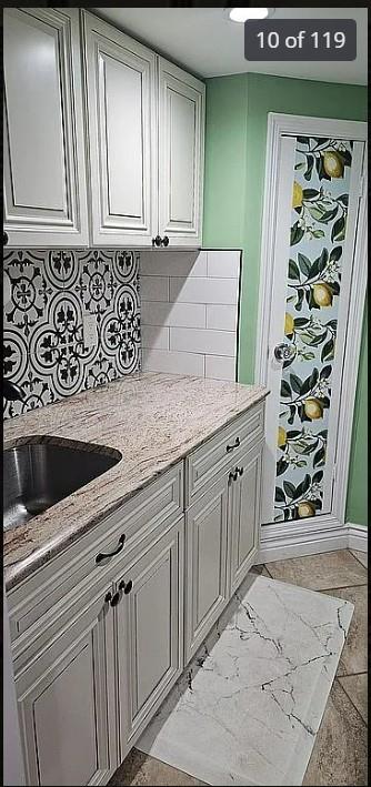 bar featuring backsplash, a sink, and baseboards