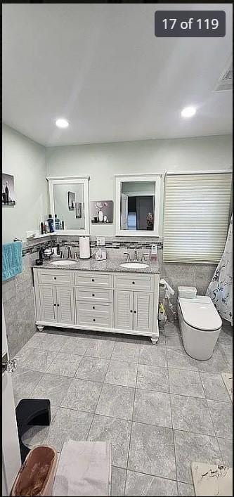 bathroom featuring toilet, double vanity, and recessed lighting