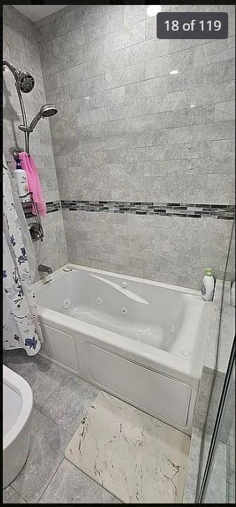 bathroom with a combined bath / shower with jetted tub