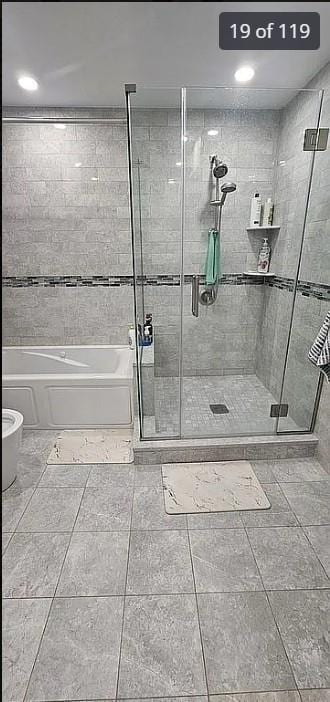 bathroom with a bath, a shower stall, and tile patterned floors