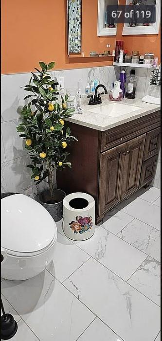 half bath with vanity, toilet, and marble finish floors