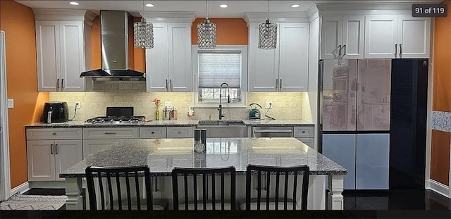 kitchen featuring wall chimney exhaust hood, a kitchen breakfast bar, a sink, backsplash, and recessed lighting