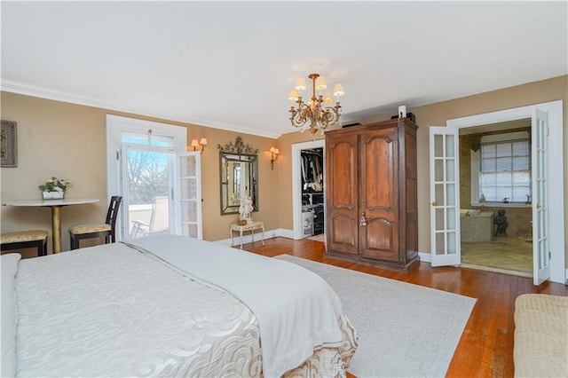 bedroom with ornamental molding, baseboards, a walk in closet, dark wood-type flooring, and a chandelier