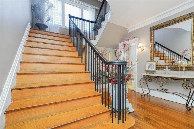staircase featuring crown molding, baseboards, and wood finished floors