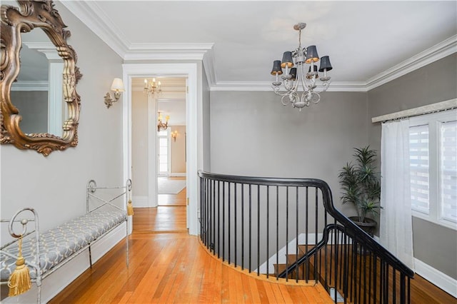 hall with a notable chandelier, a healthy amount of sunlight, and an upstairs landing