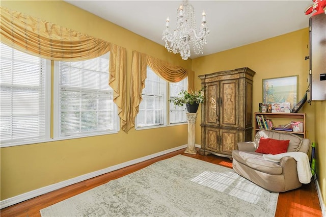 living area featuring baseboards, wood finished floors, and a notable chandelier