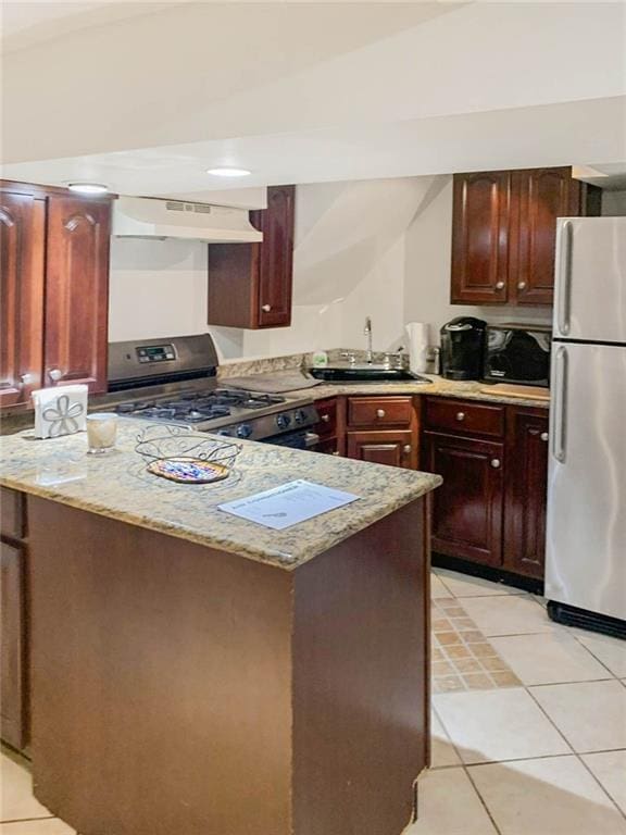 kitchen featuring appliances with stainless steel finishes, a sink, light tile patterned floors, light stone counters, and under cabinet range hood