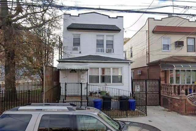 view of front facade with a gate, a fenced front yard, a shingled roof, and an AC wall unit