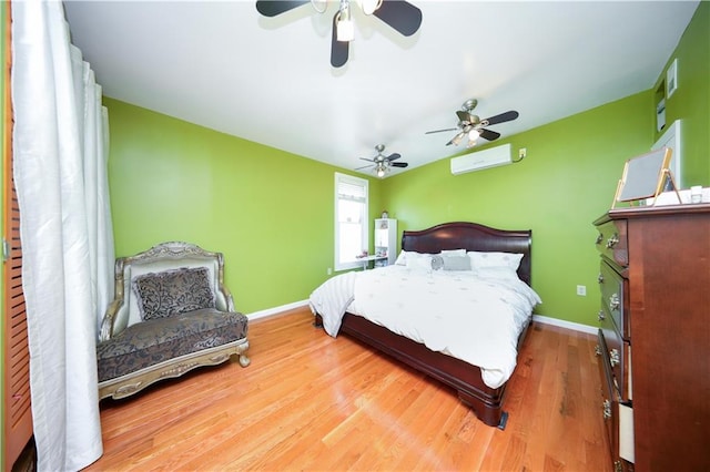 bedroom with a ceiling fan, a wall mounted AC, wood finished floors, and baseboards