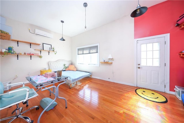 interior space with wood finished floors, a wall mounted air conditioner, baseboards, and multiple windows
