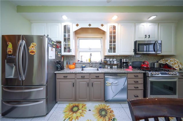 kitchen with white cabinetry, stainless steel appliances, glass insert cabinets, and a sink
