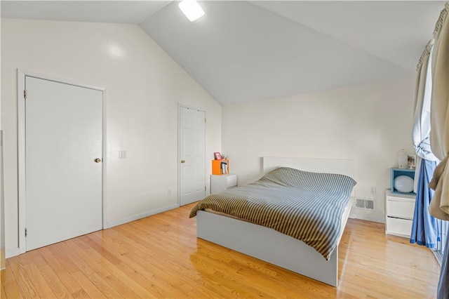 bedroom with lofted ceiling, visible vents, and light wood-style flooring