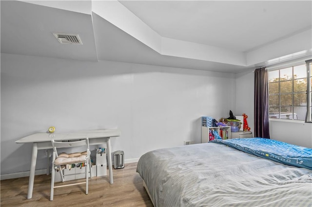 bedroom with wood finished floors, visible vents, and baseboards