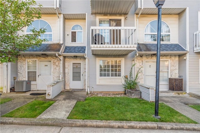 townhome / multi-family property featuring a front yard, central AC unit, and a balcony