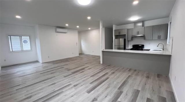 kitchen featuring freestanding refrigerator, gray cabinets, a sink, black range, and light wood-type flooring