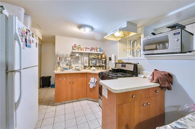 1639 Hendrickson St, Brooklyn, NY 11234 - kitchen with white appliances, under cabinet range hood, light countertops, light tile patterned floors, and brown cabinets