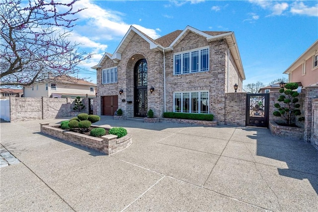 traditional home with fence, a gate, and brick siding